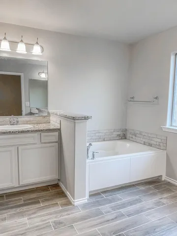 a spacious bathroom with a tub sink and a mirror