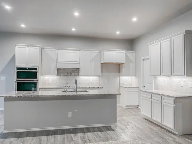 a kitchen with kitchen island granite countertop a sink window and cabinets