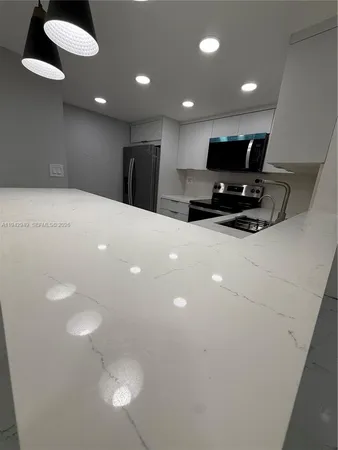 a kitchen with stainless steel appliances a refrigerator a stove a microwave and white cabinets