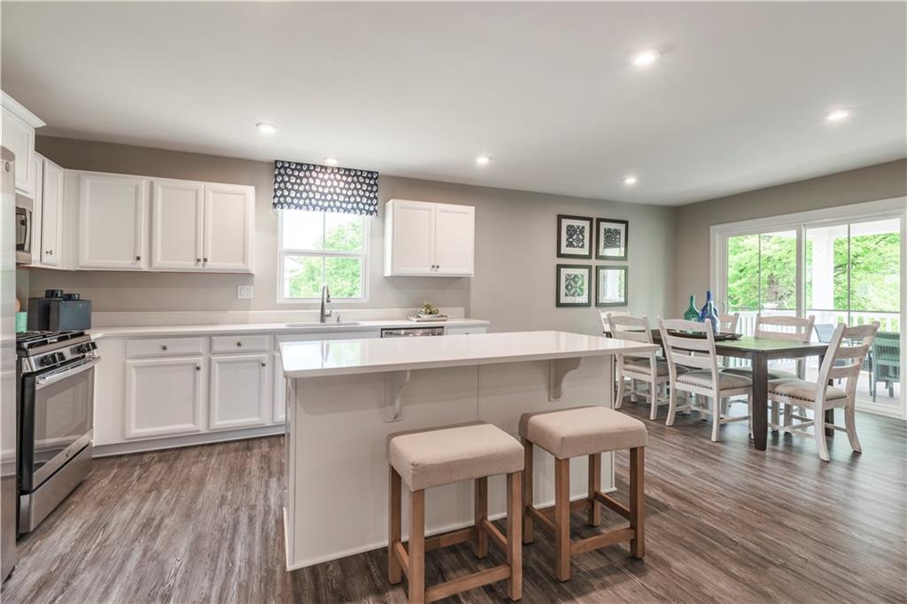 844 Ashley Road Gibsonia, PA 15044 - Photo 7 of 16 a kitchen with cabinets a sink dishwasher a dining table and chairs with wooden floor