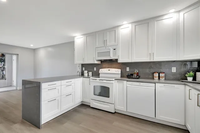 a kitchen with white cabinets white stainless steel appliances and sink