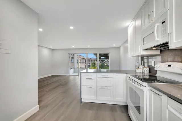 a kitchen with granite countertop white cabinets and white appliances