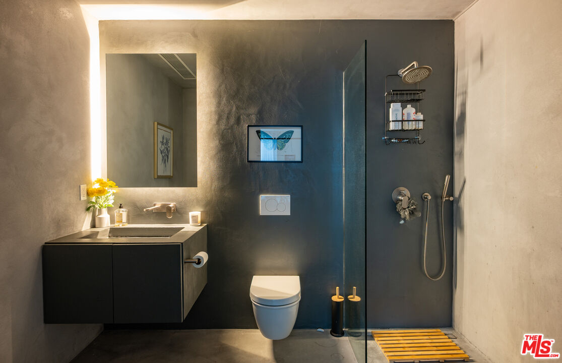 7681 Willow Glen Road Los Angeles, CA 90046 - Photo 49 of 71 a bathroom with a granite countertop toilet a sink and mirror