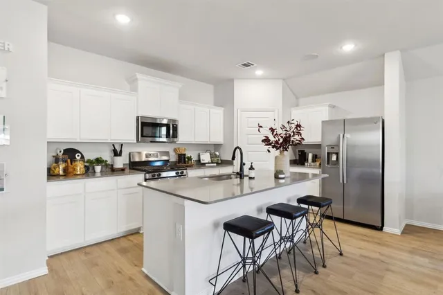 a kitchen with sink a refrigerator and chairs