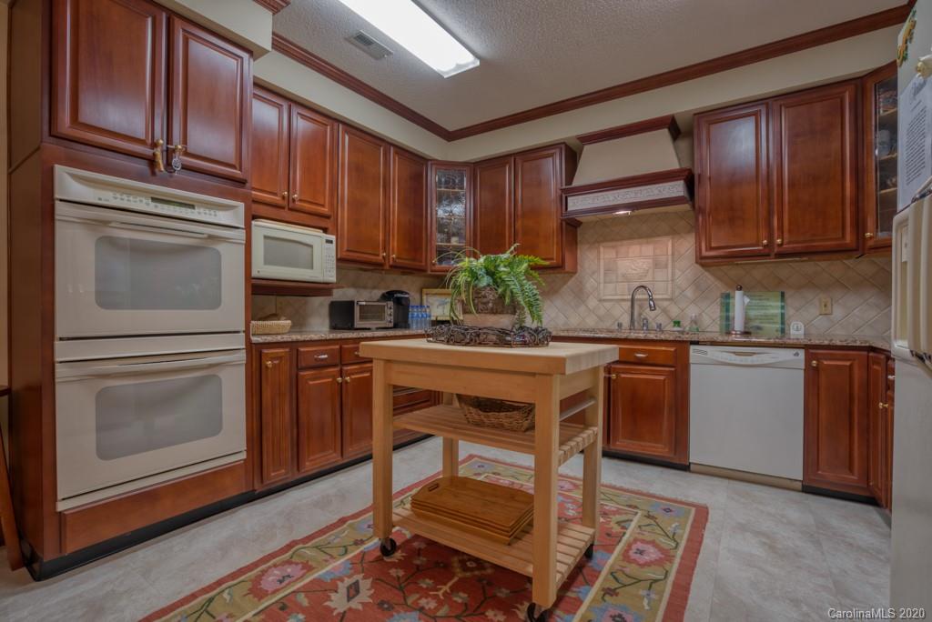 77 Club Road Tryon, NC 28782 - Photo 18 of 35 a kitchen with stainless steel appliances granite countertop wooden cabinets a sink and dishwasher a stove with wooden floor