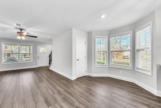 a view of an empty room with a window and wooden floor