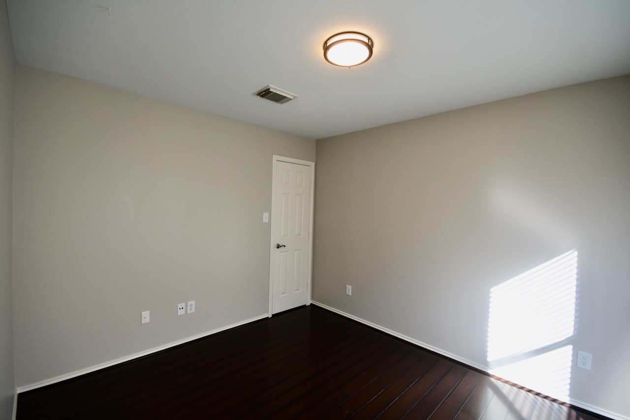 1706 Redwing Bluff Drive Houston, TX 77009 - Photo 16 of 24 a view of an empty room with wooden floor and a window