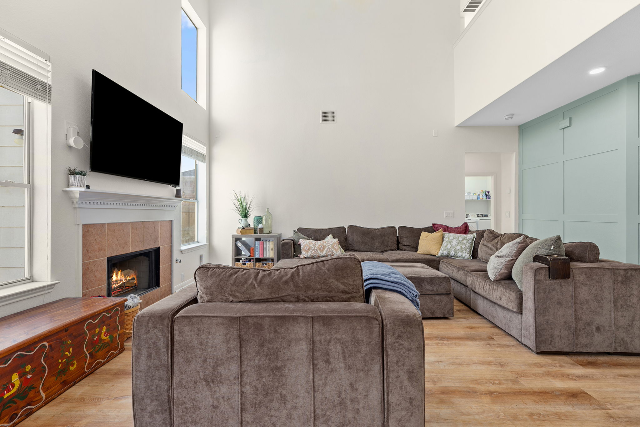 3517 Shiraz Loop Round Rock, TX 78665 - Photo 6 of 40 Spacious living area featuring high ceilings, wood-finish flooring, a tile-surround fireplace with mantel, large windows, and a decorative accent wall
