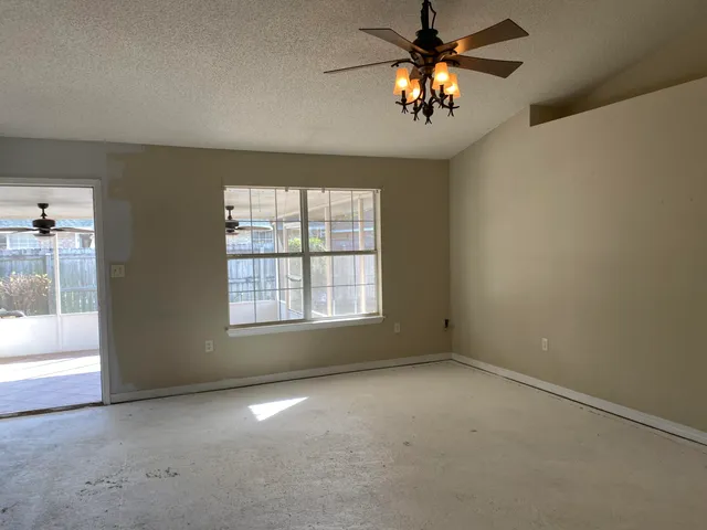 an empty room with windows and chandelier fan