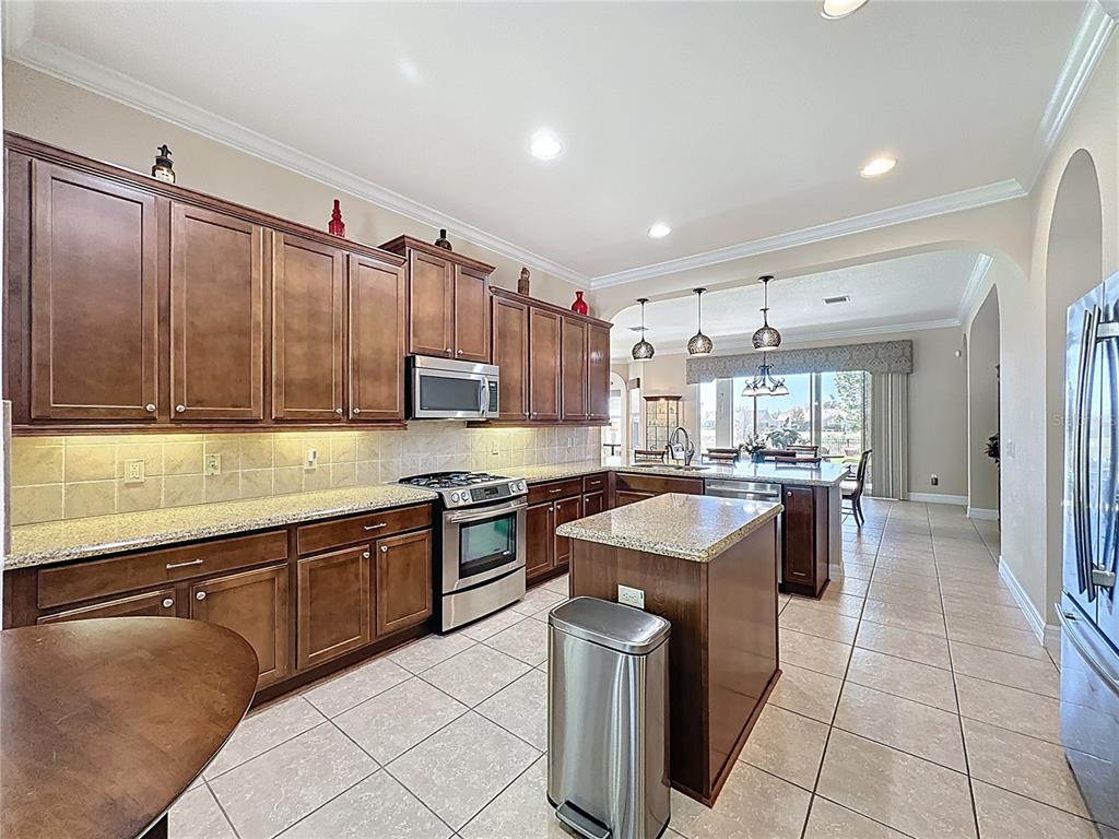 228 Bayou Bend Road Groveland, FL 34736 - Photo 9 of 54 a kitchen with kitchen island granite countertop a sink counter top space cabinets and stainless steel appliances