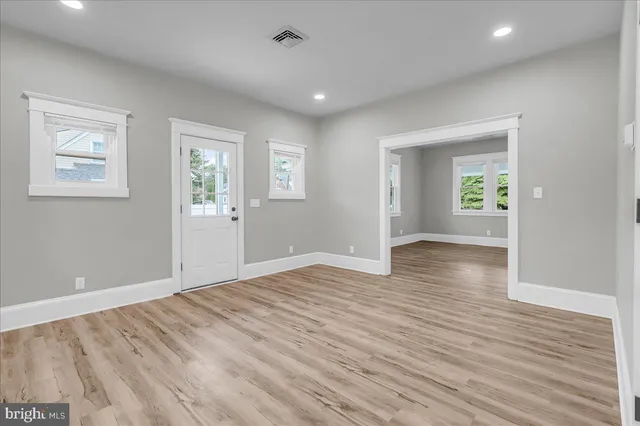 an empty room with wooden floor and windows