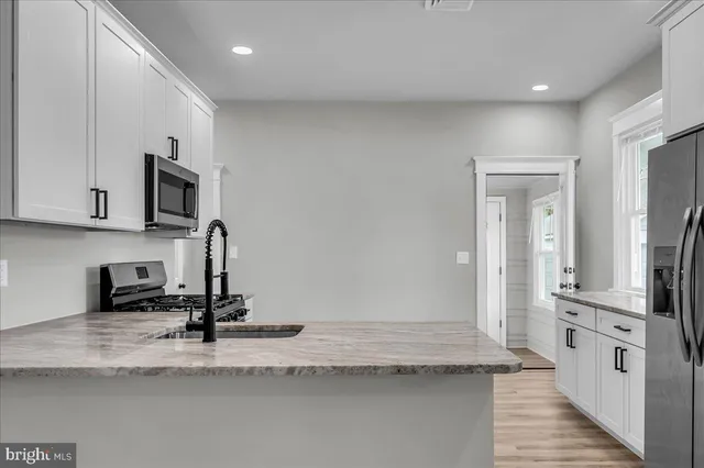 a kitchen with granite countertop a stove sink and microwave