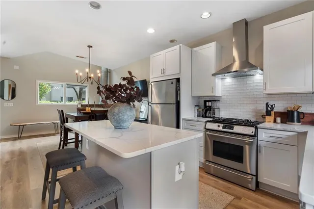 a kitchen with a stove a refrigerator and chairs