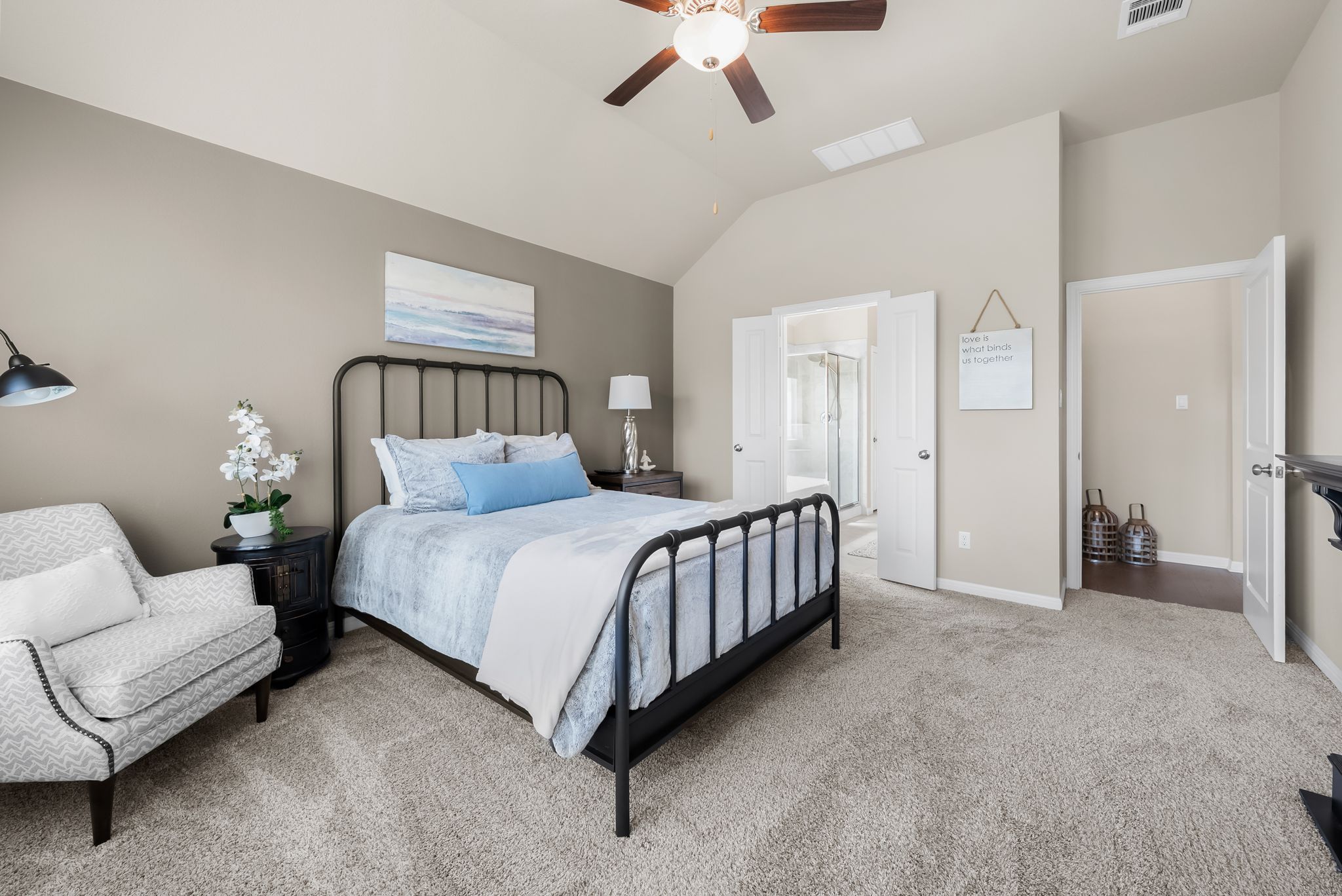 300 Prato Place Georgetown, TX 78628 - Photo 17 of 40 An inviting bedroom with plush carpeting and vaulted ceilings, featuring a private ensuite bathroom entrance.