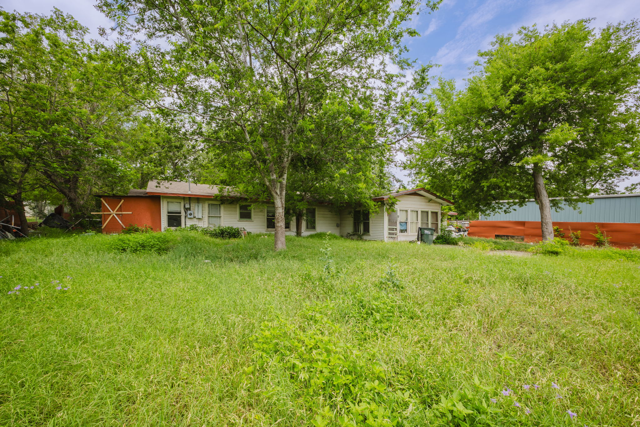 6803 Viewing Place Austin, TX 78719 - Photo 14 of 20 A verdant, overgrown lot surrounds this single-level dwelling, offering potential for outdoor customization.