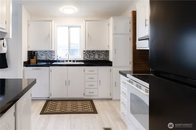 a kitchen with granite countertop a sink stove and cabinets