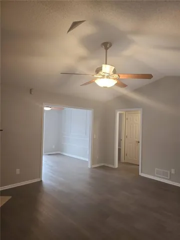 an empty room with a chandelier fan and windows