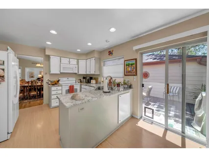 a kitchen with stainless steel appliances granite countertop a refrigerator a sink a stove and white cabinets with wooden floor