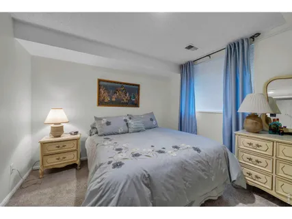 a bedroom with a bed a dresser and painting