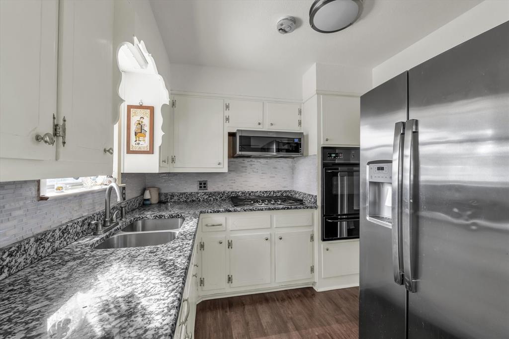 309 South Rita Street Lacy-Lakeview, TX 76705 - Photo 8 of 19 Kitchen featuring stainless steel appliances, backsplash, dark stone countertops, dark wood finished floors, and a warming drawer