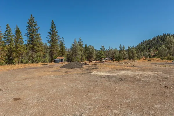a view of dirt field with trees in background