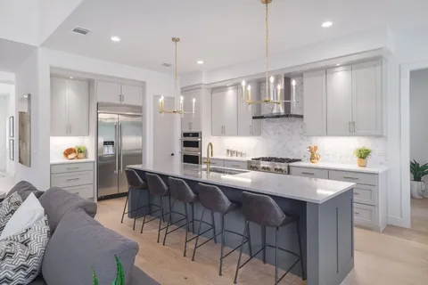 a kitchen with stainless steel appliances granite countertop a sink a stove a refrigerator and chairs