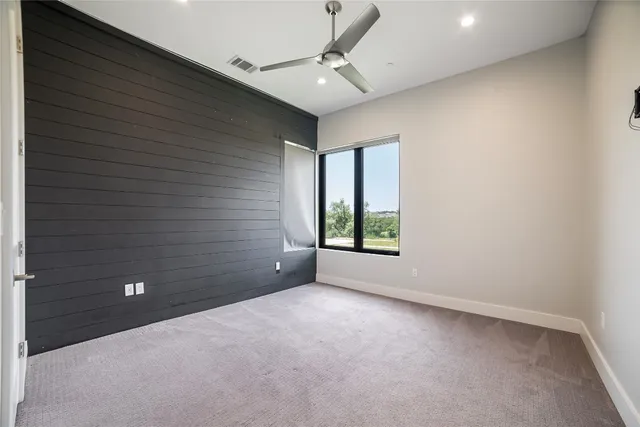 en empty room with windows and ceiling fan