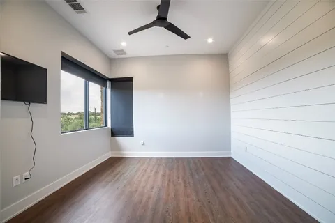 a view of empty room with wooden floor and fan