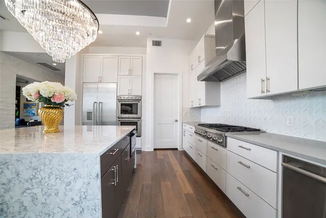 a large kitchen with stainless steel appliances granite countertop a lot of counter space and wooden floor