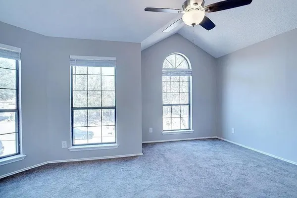 an empty room with windows chandelier fan and windows