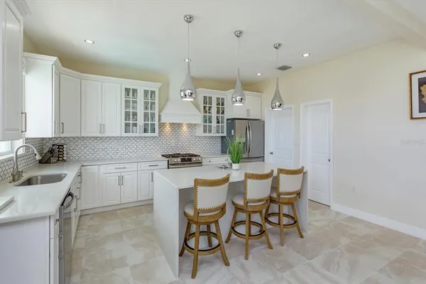 a kitchen with a sink chairs and white cabinets