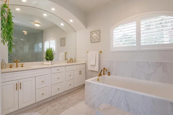 a bathroom with a granite countertop sink mirror and a bathtub