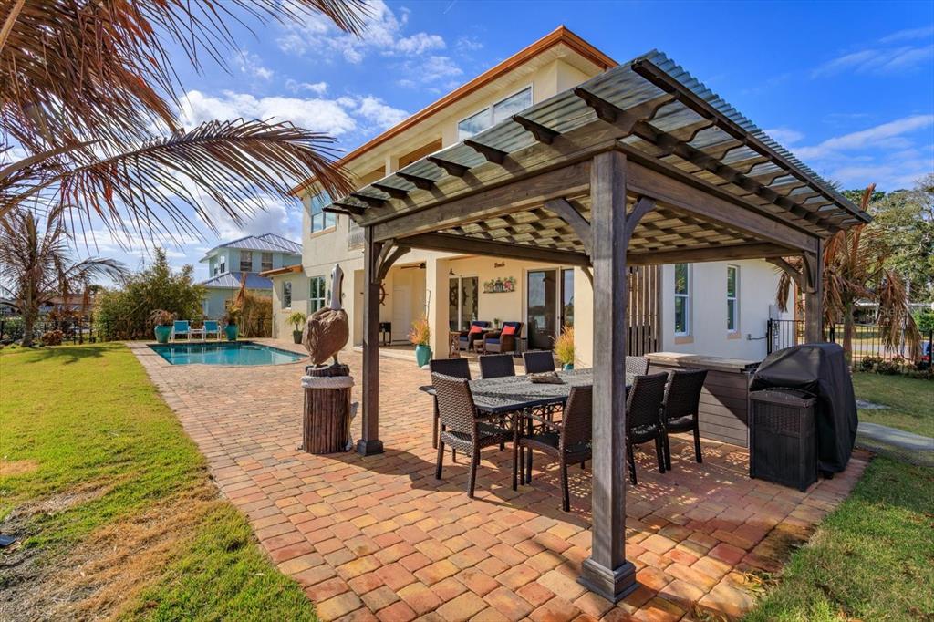 1201 South Riverside Drive Edgewater, FL 32132 - Photo 41 of 47 a view of a patio with a table and chairs under an umbrella with a barbeque grill and plants