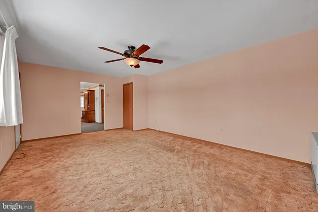 a view of a big room with a window and a ceiling fan