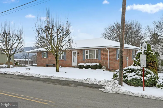 a front view of a house with a yard covered in snow