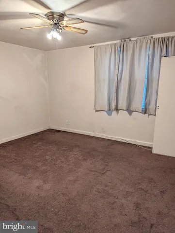 en empty room with stairs and a fan