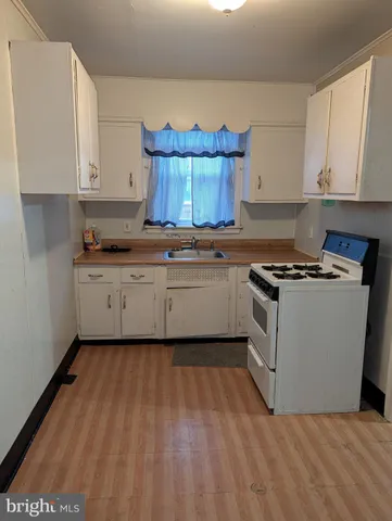 a kitchen with granite countertop a stove a sink dishwasher and a microwave oven with white cabinets