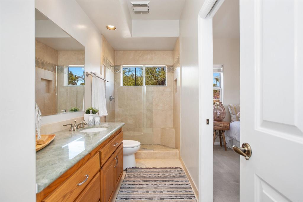 29076 Sunset Road Valley Center, CA 92082 - Photo 31 of 65 a bathroom with a granite countertop sink a mirror and a shower