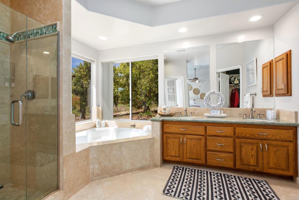 29076 Sunset Road Valley Center, CA 92082 - Photo 36 of 65 a bathroom with a granite countertop sink a large mirror a shower and a bathtub