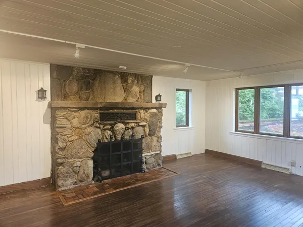 an empty room with wooden floor entryway and windows