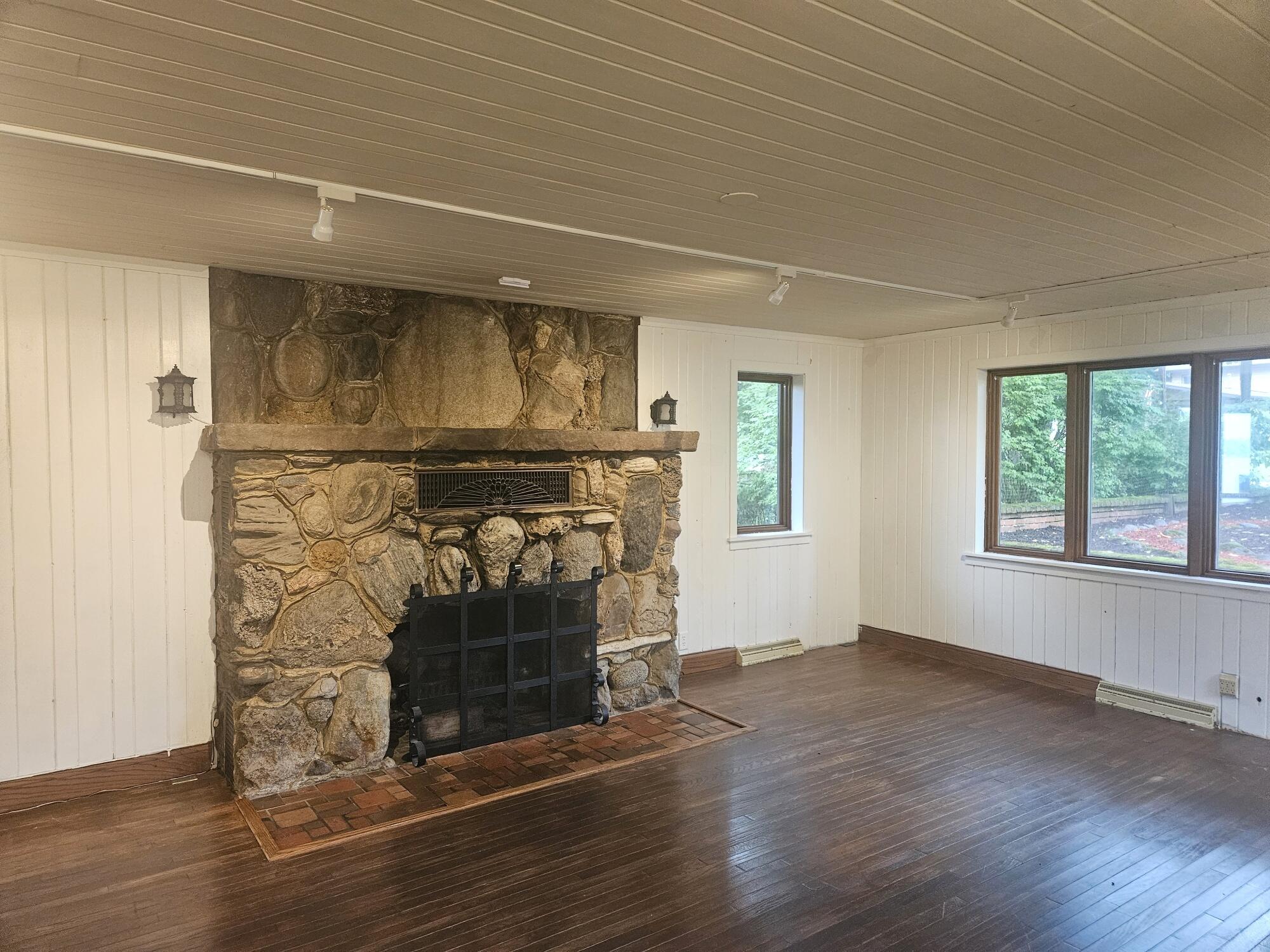 683 Waverly Road La Porte, IN 46350 - Photo 16 of 54 an empty room with wooden floor fireplace and windows