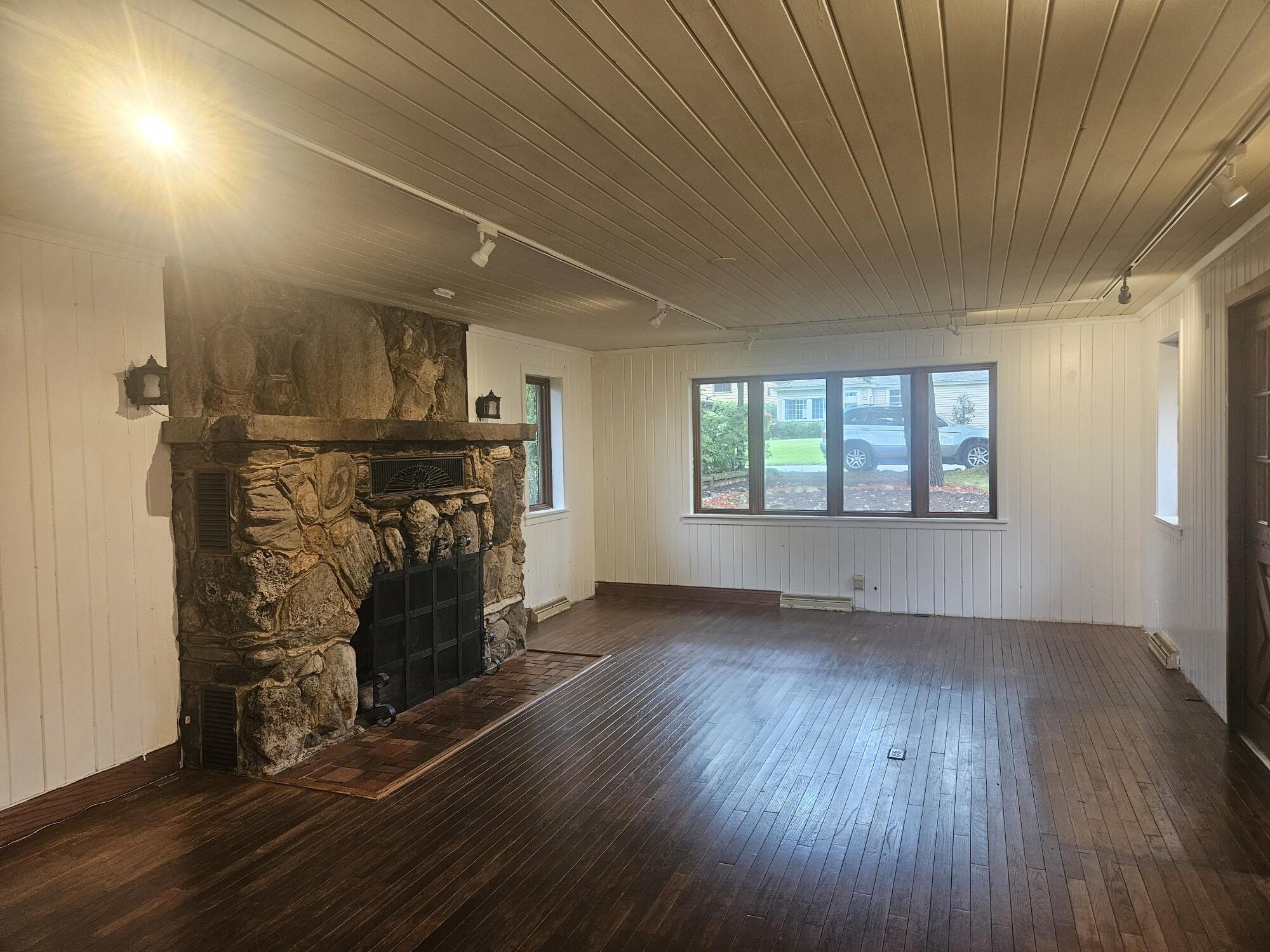683 Waverly Road La Porte, IN 46350 - Photo 17 of 54 an empty room with wooden floor fireplace and windows