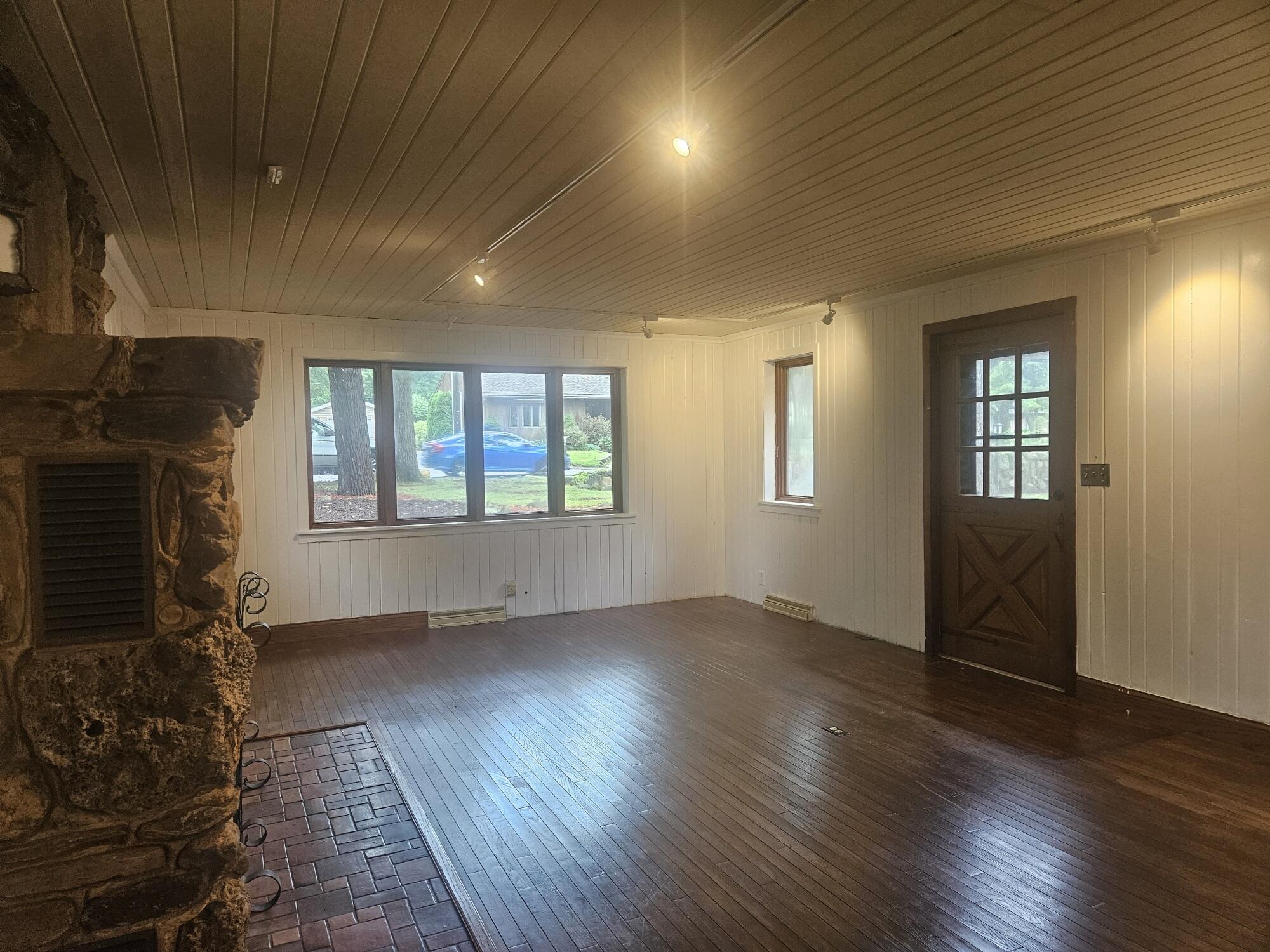 683 Waverly Road La Porte, IN 46350 - Photo 18 of 54 an empty room with wooden floor fireplace and windows