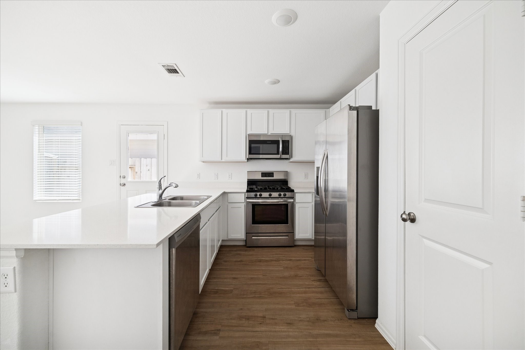 19642 Rupetti Drive New Caney, TX 77357 - Photo 4 of 14 a kitchen with kitchen island granite countertop stainless steel appliances cabinets a sink and a wooden floor