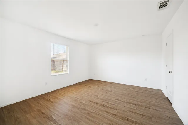 an empty room with wooden floor and windows