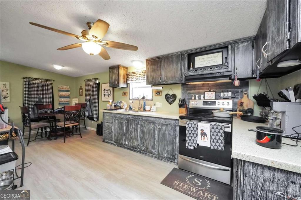 926 Silver Dollar Road Milner, GA 30257 - Photo 6 of 15 a kitchen with stainless steel appliances granite countertop a stove top oven a sink a dining table and chairs with wooden floor