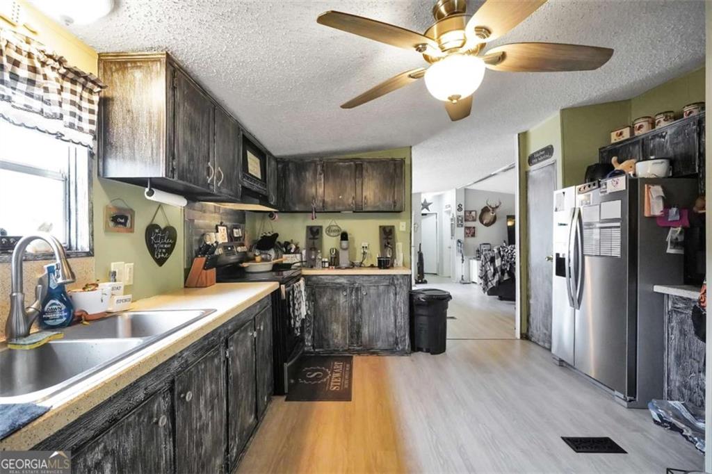 926 Silver Dollar Road Milner, GA 30257 - Photo 7 of 15 a kitchen with stainless steel appliances granite countertop a refrigerator a sink dishwasher a stove and a dining table with wooden floor