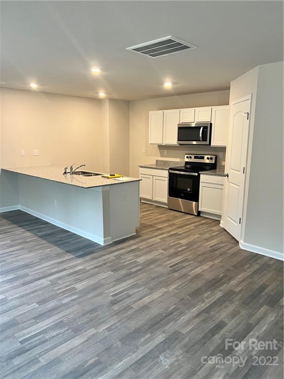 4852 Stone Drive, Unit 127 Conover, NC 28613 - Photo 9 of 34 a kitchen with stainless steel appliances wooden floor and a refrigerator