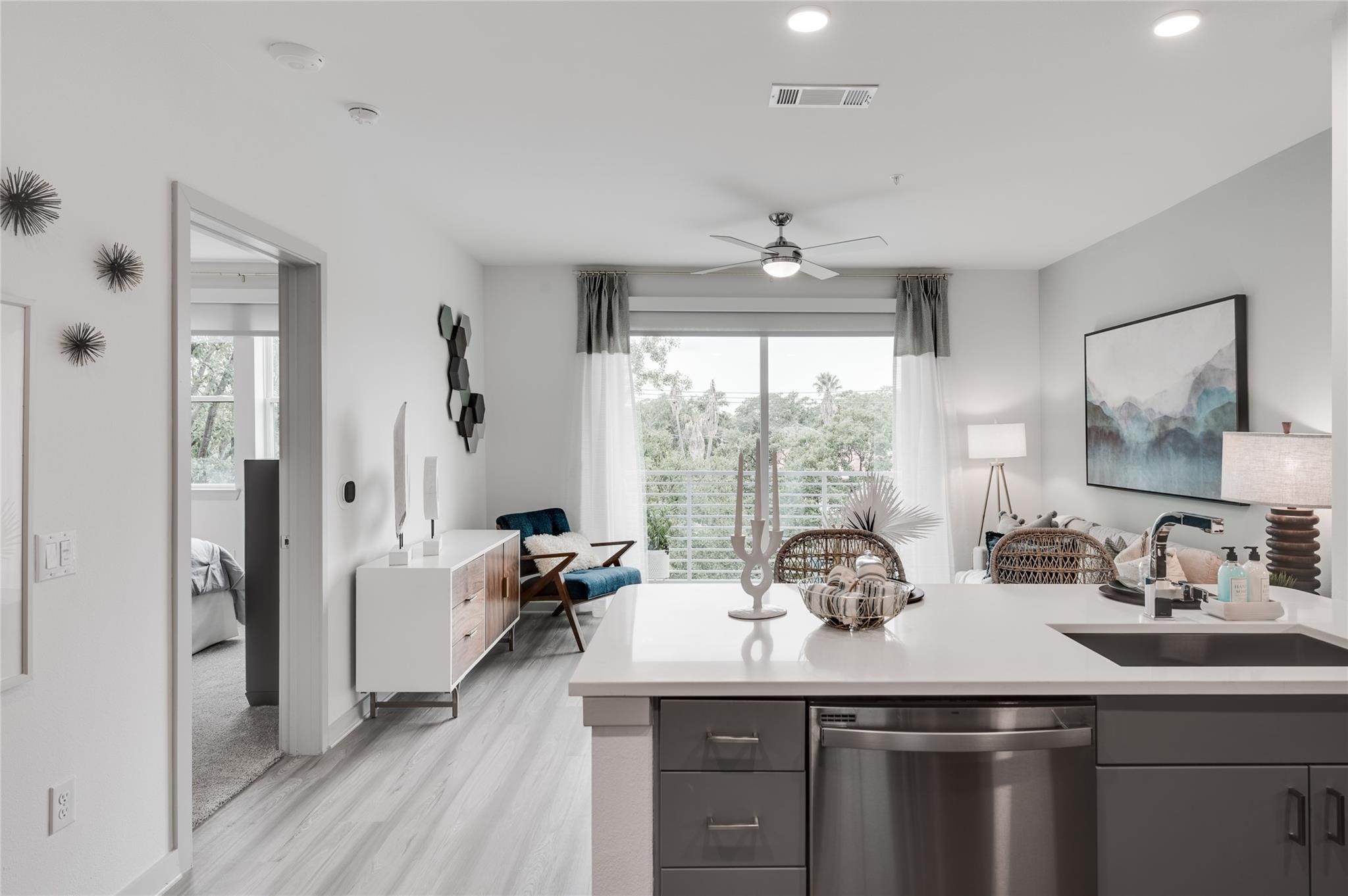 Experience the elegance of this modern open-plan kitchen and living area, featuring sleek cabinetry, stainless steel appliances, and abundant natural light from a large sliding glass window leading to the balcony.