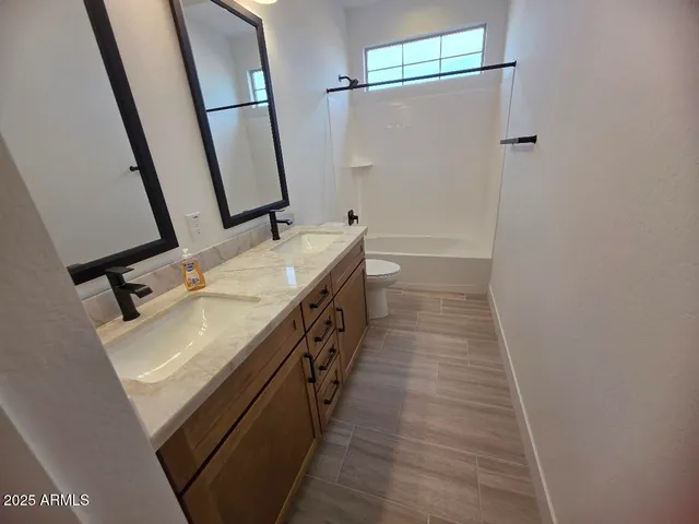 a bathroom with a sink a mirror a vanity and a toilet